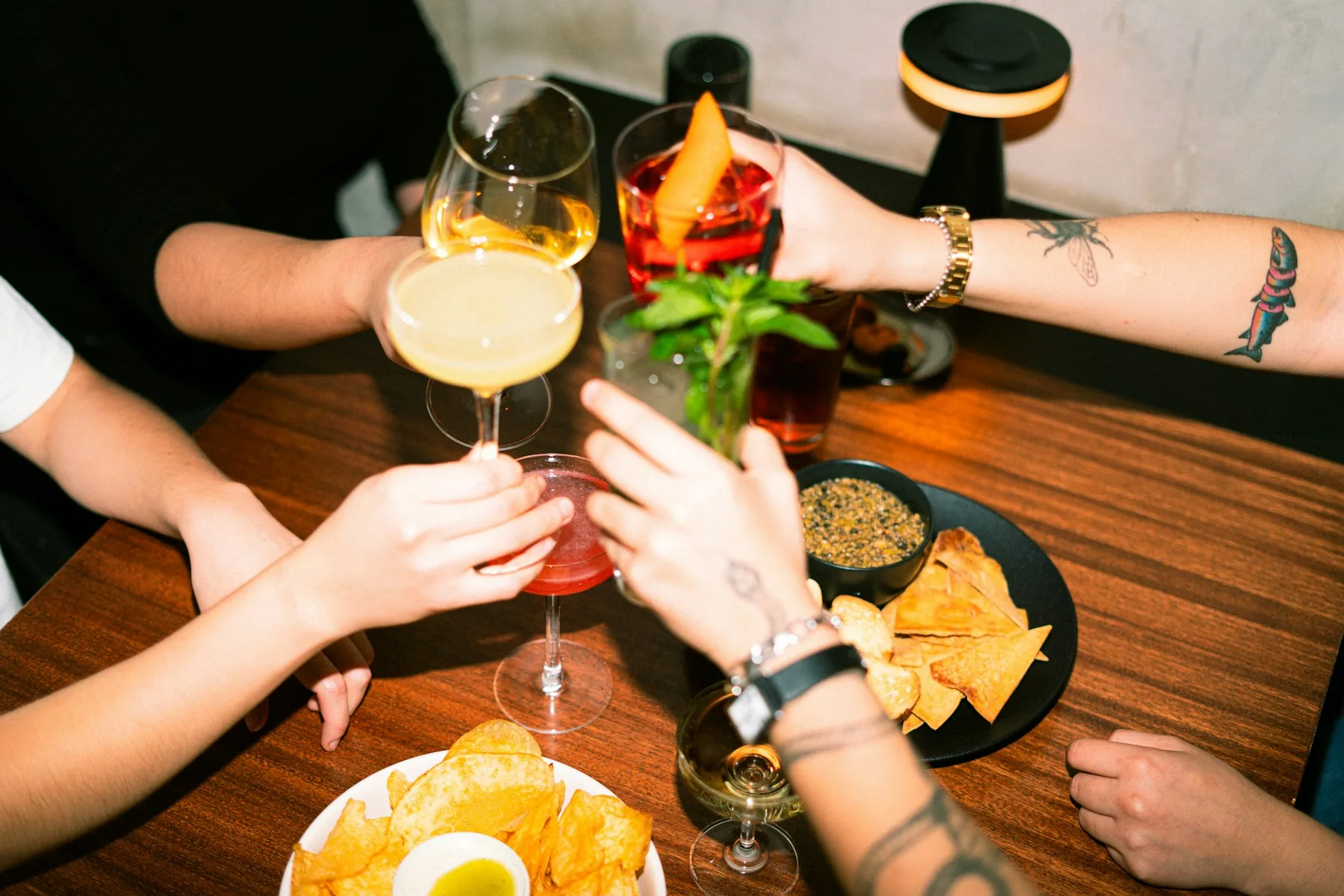 Friends sharing a toast with cocktails around the table